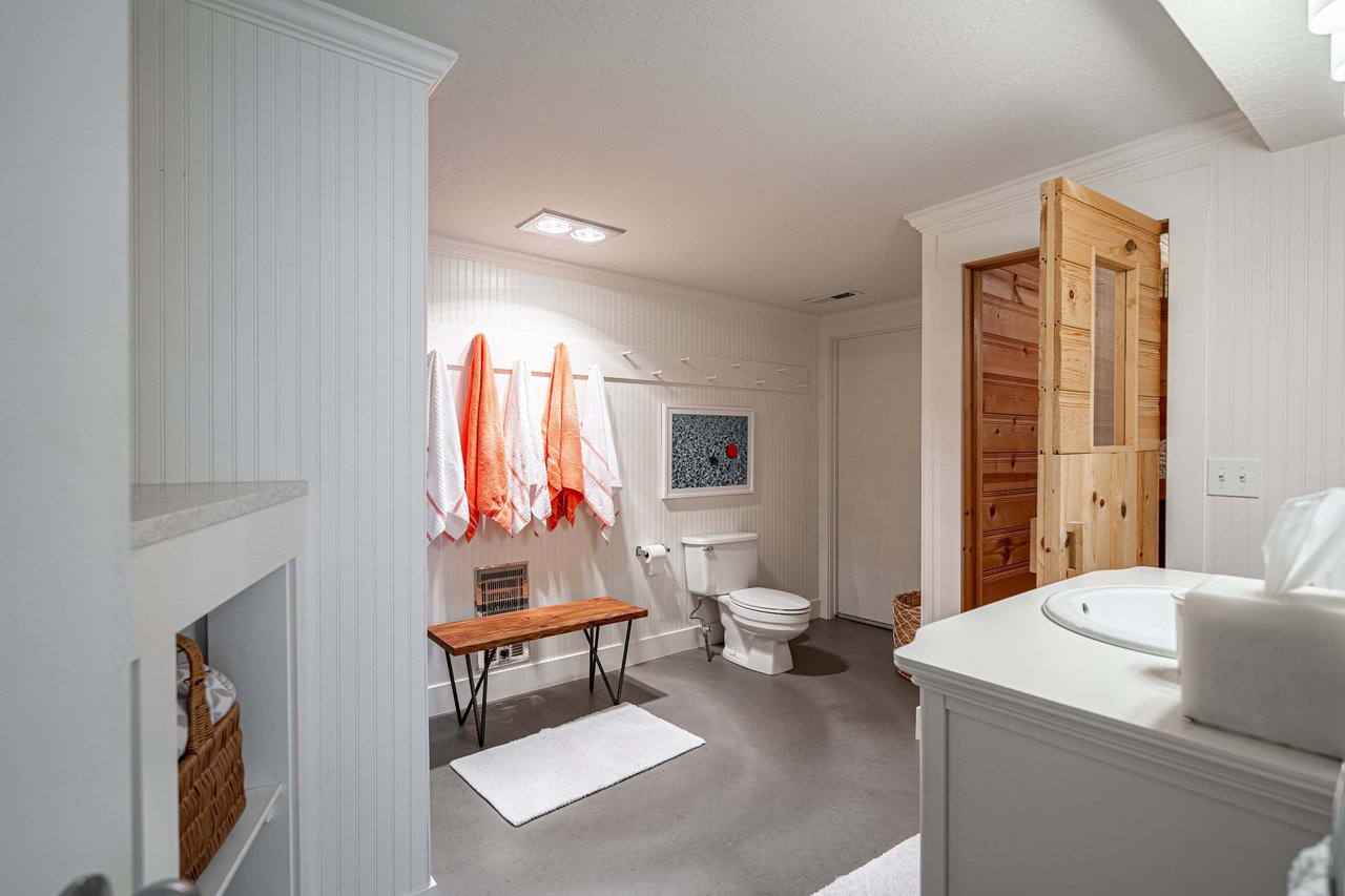 A white bathroom with beadboard walls and light gray floor tiles.