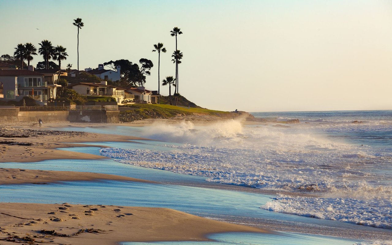 La Jolla sandy beach during the day with surfers and waves crashing.