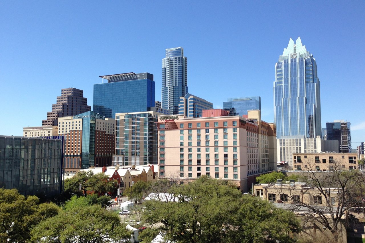 A view of the skyline of a city with tall buildings and trees in the foreground in Austin Texas