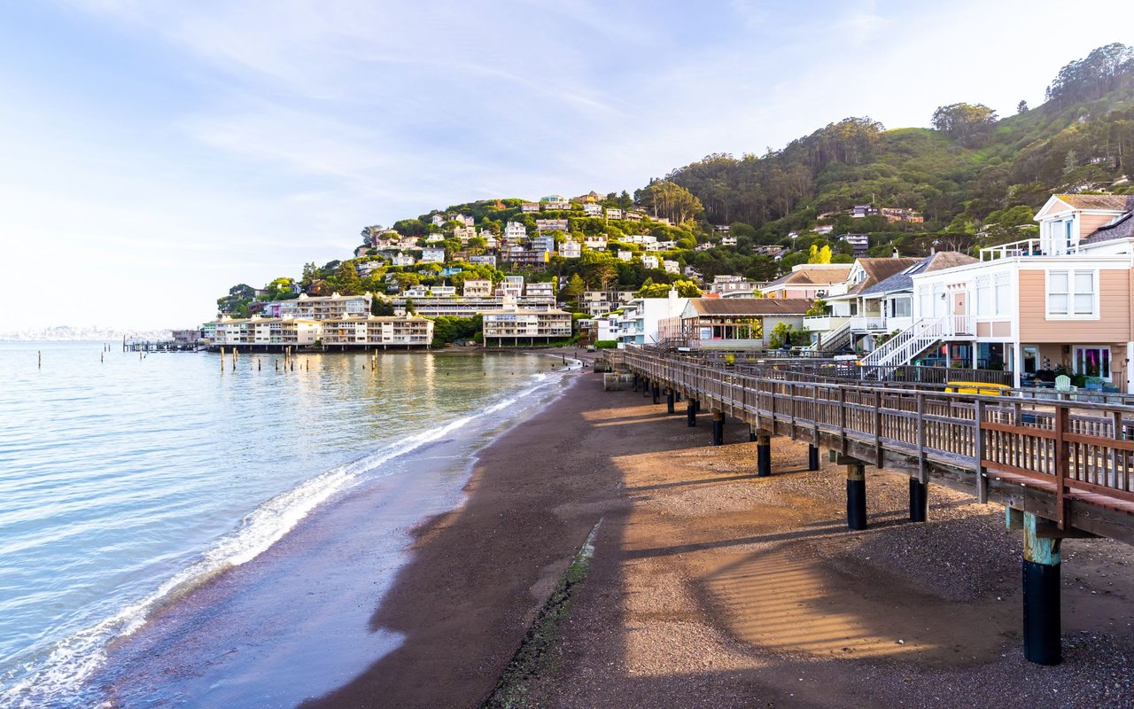 A long wooden boardwalk stretches along a sandy beach.