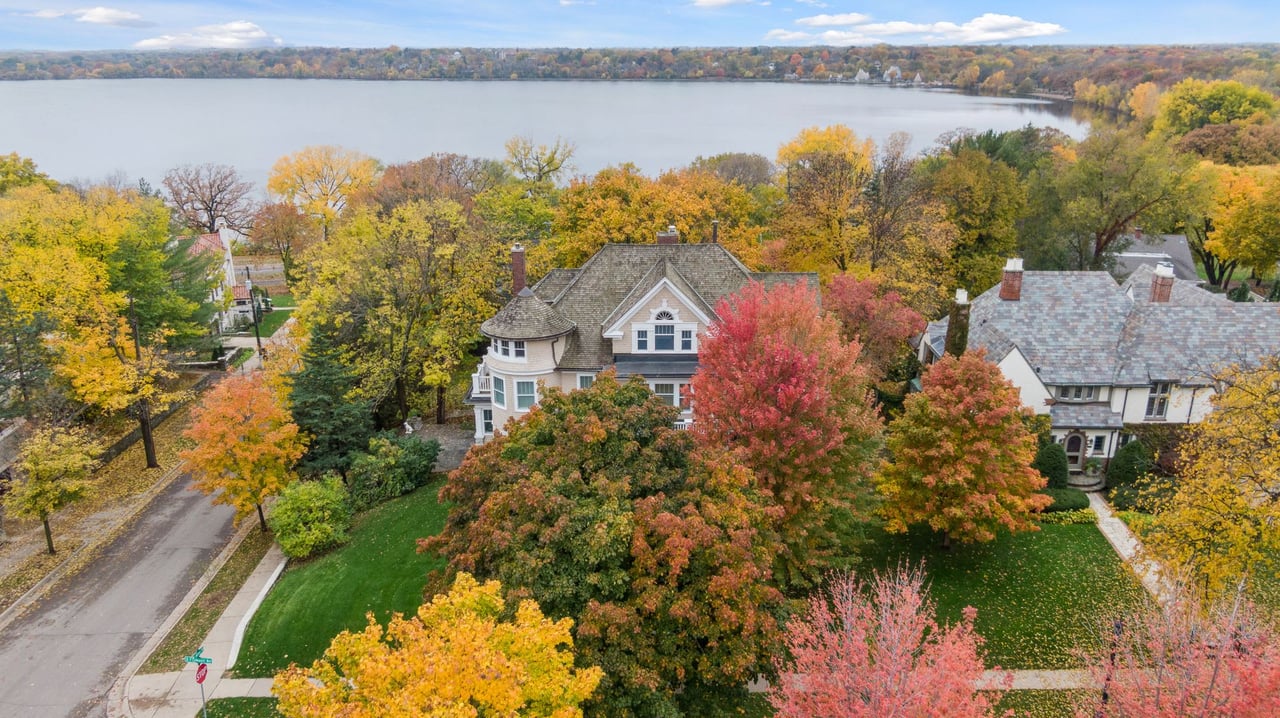 An aerial view of a house surrounded by trees in fall.