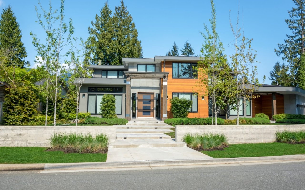 A modern house with a clean-cut design and a concrete walkway leading up to the front door.