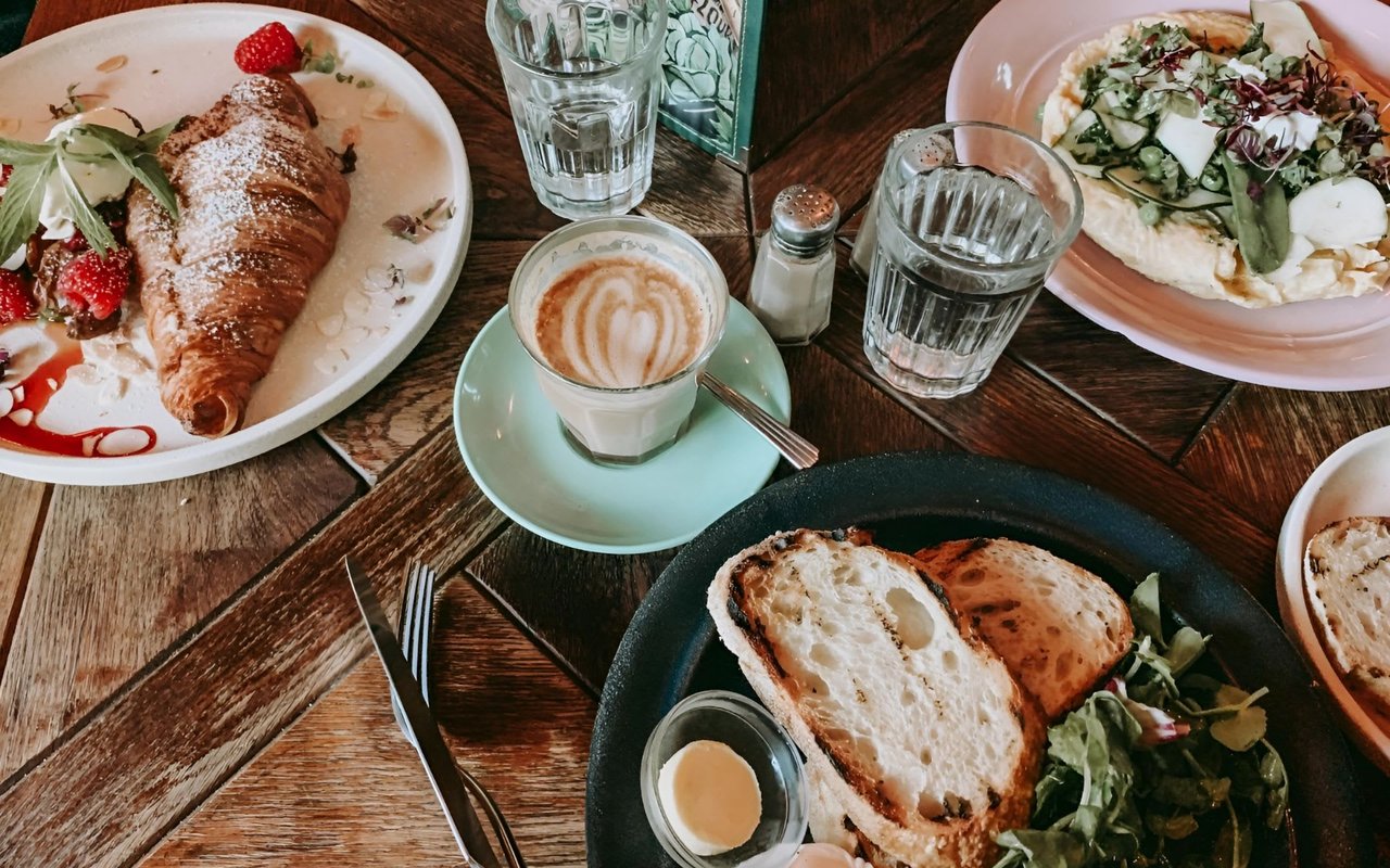  A warm, overhead shot of a wooden table laden with various breakfast and beverage items
