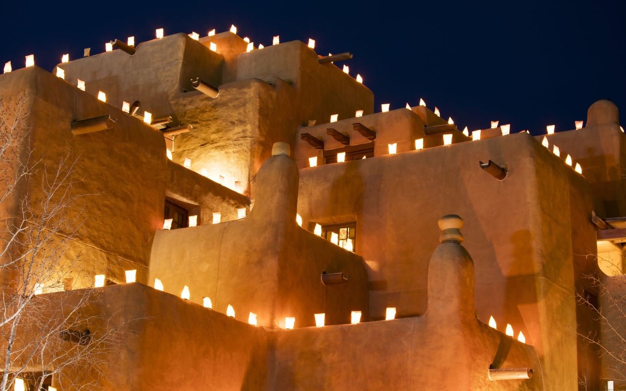 A row of adobe buildings with glowing windows and walls at night.