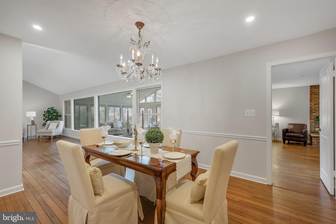 Furnished dining room with a crystal chandelier, hardwood floors, and large windows.