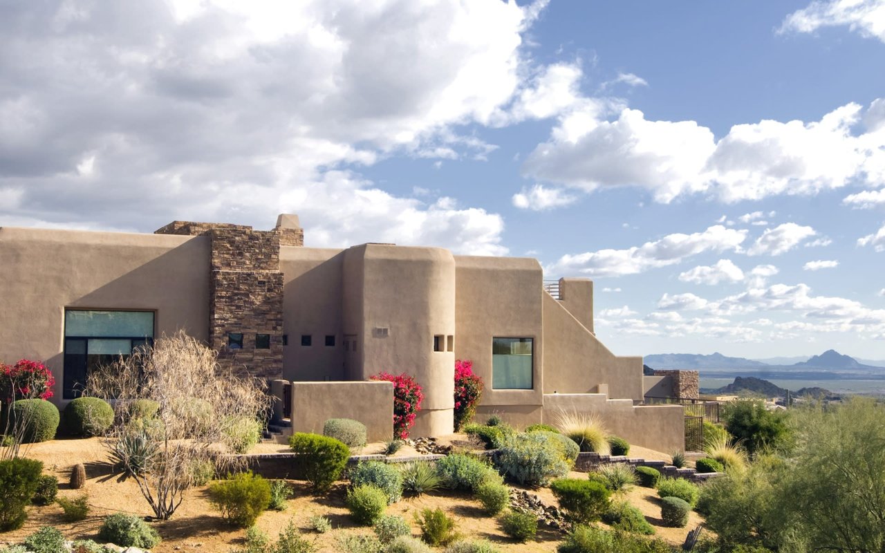 ontemporary desert retreat with a stucco home featuring stone accents and abundant natural light.