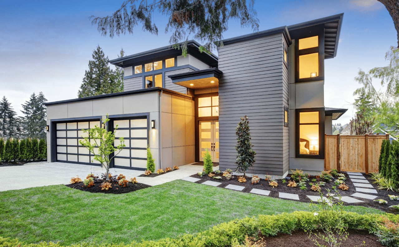 A modern house with a glass garage door and a lush green yard