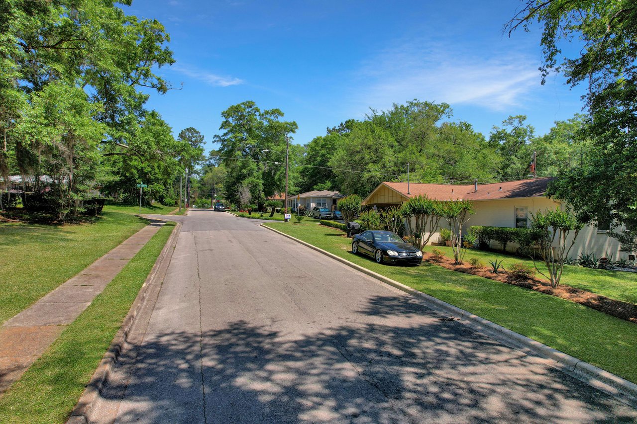 A street-level view of a residential street in Tuskegee. The road is lined with houses and trees, and the neighborhood appears quiet and well-kept.