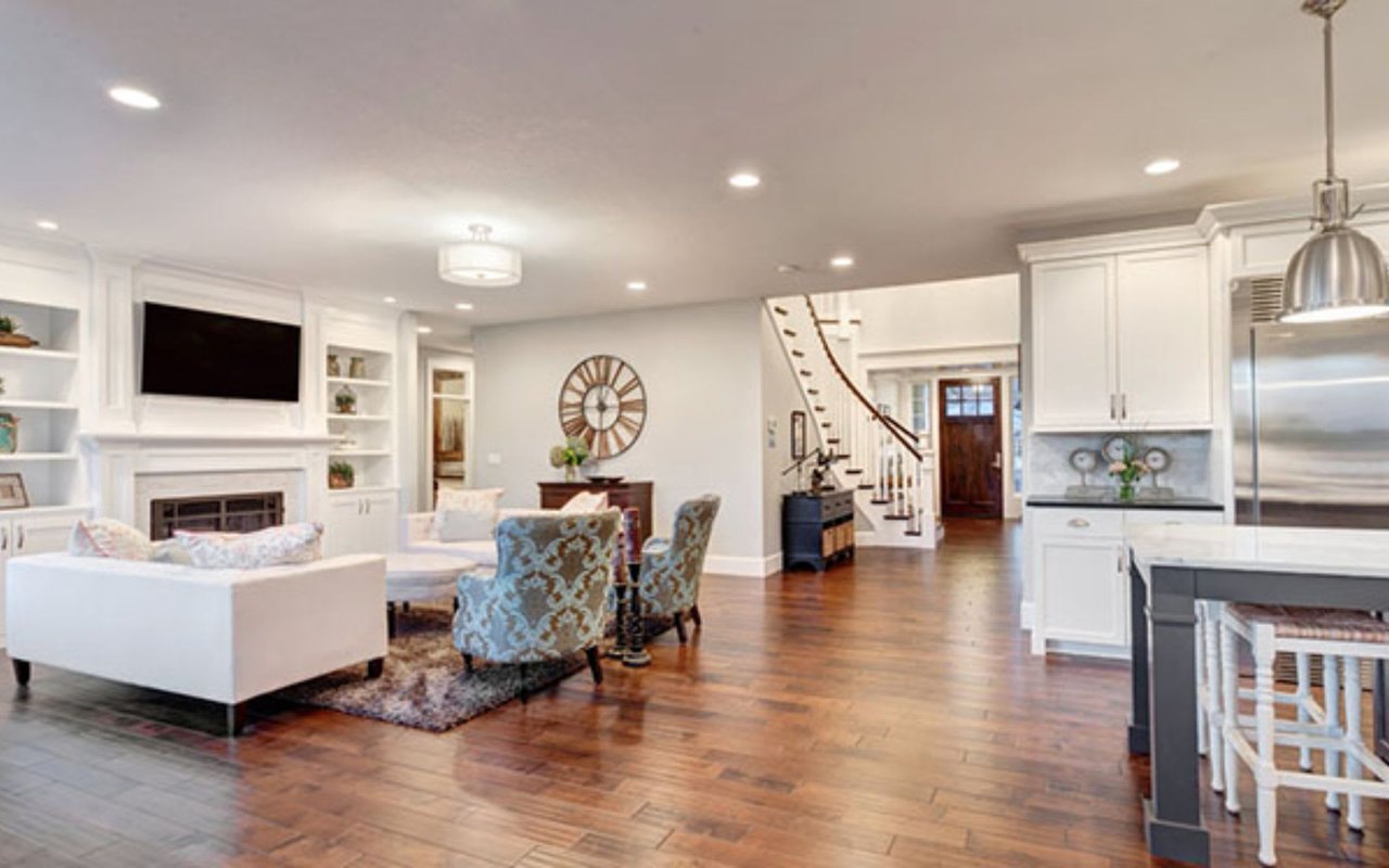 a modern kitchen island with a dark base and light countertop has three woven bar stools tucked underneath.