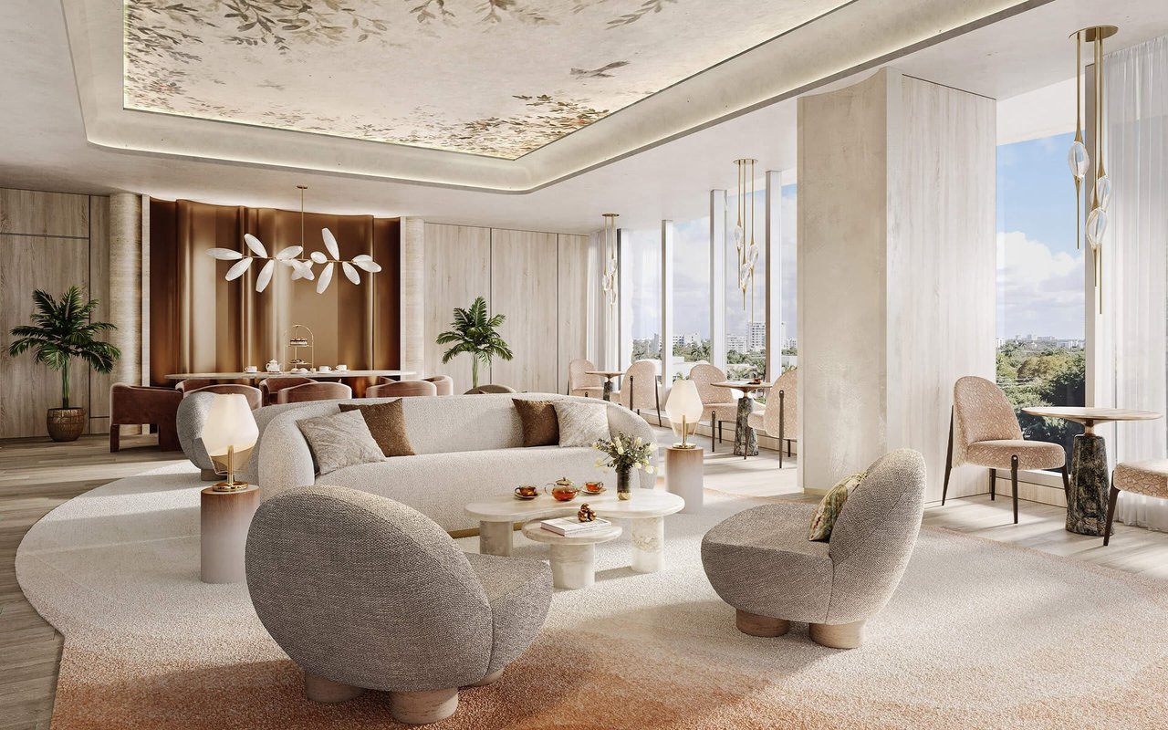 Furnished luxury lounge with curved seating, sculptural lighting, and windows overlooking greenery and the city.