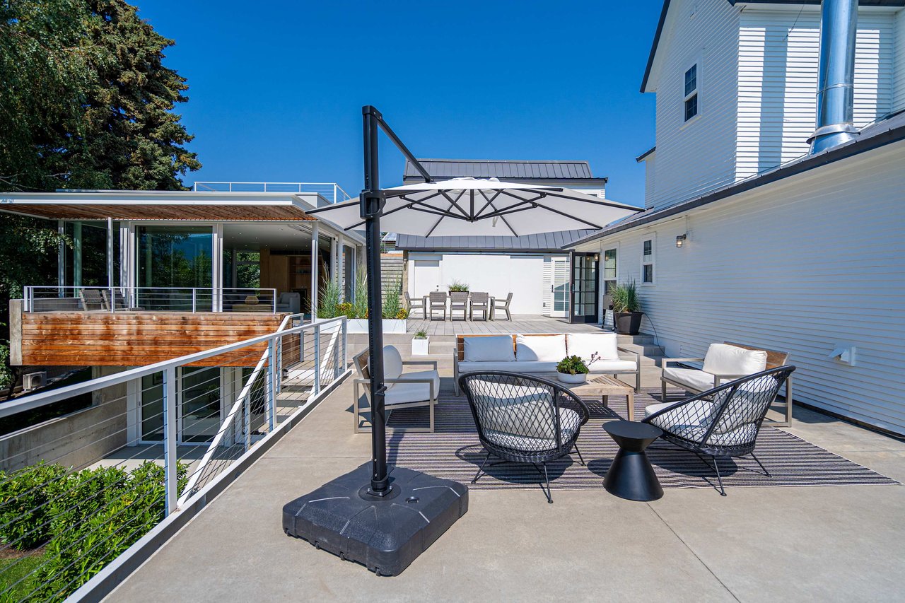 An inviting outdoor patio with a patterned black and white rug, featuring a white outdoor sofa 