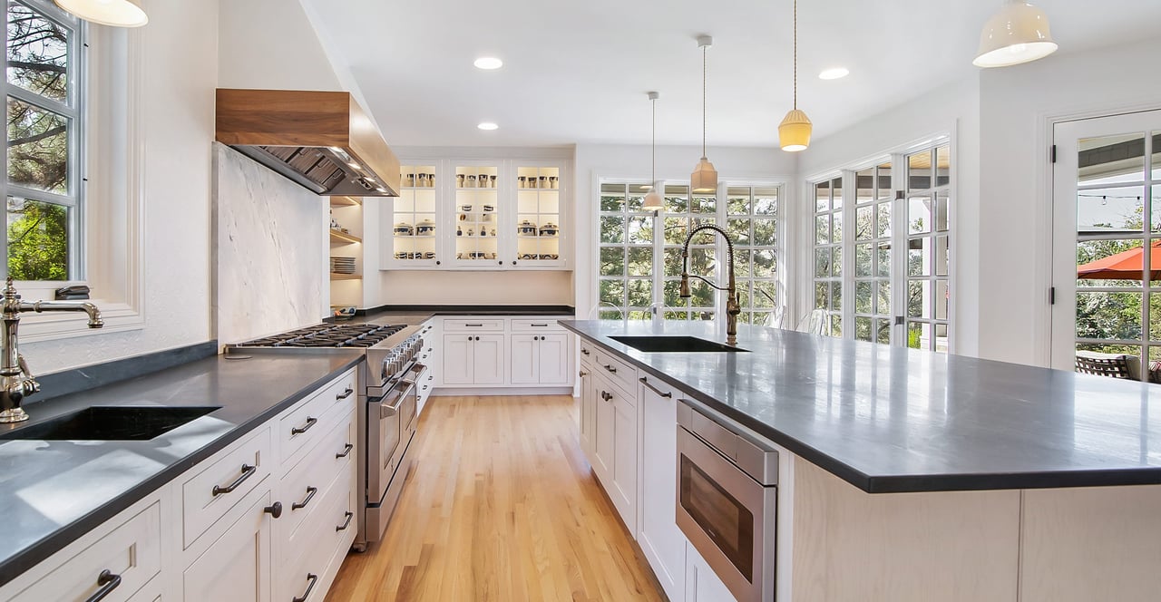 White kitchen with stainless steel appliances, white cabinets, and a large island with seating