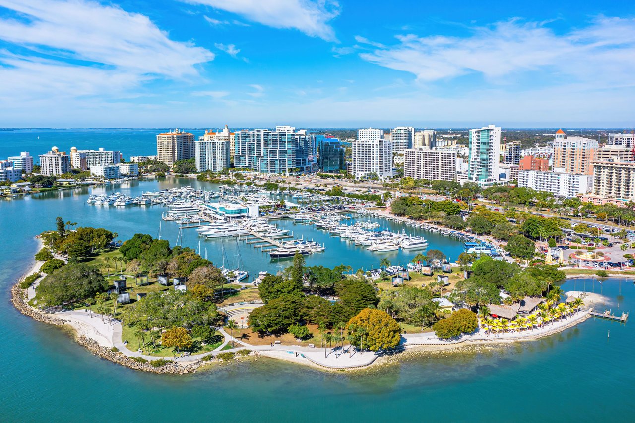 Bustling marina lined with modern high-rises, surrounded by lush greenery.