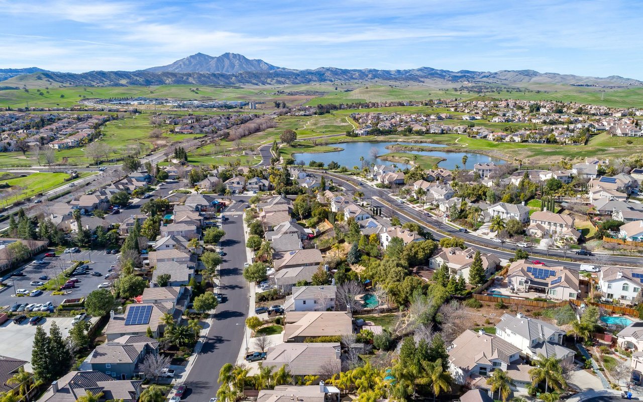 An aerial view of a residential neighborhood with a river or lake in the background