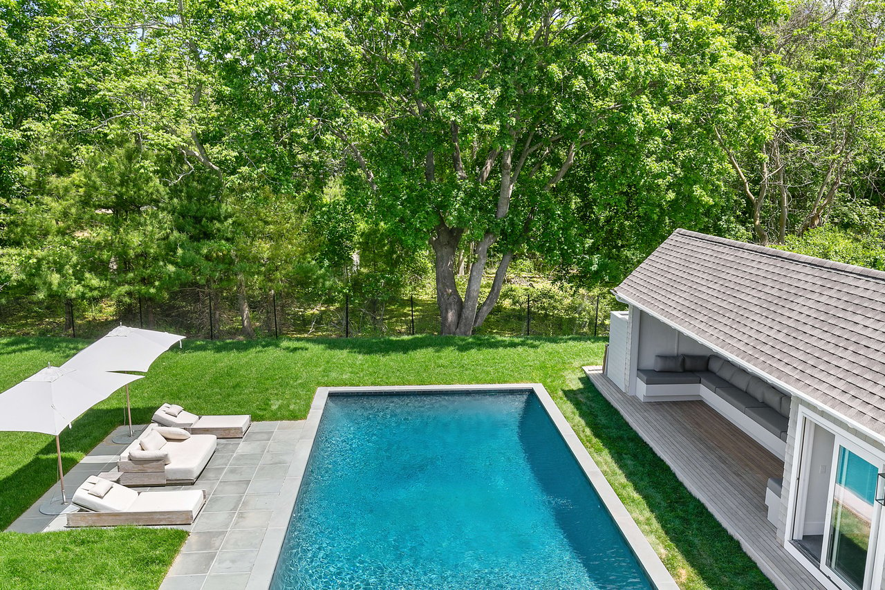 Backyard with a rectangular swimming pool, lounge chairs, and a poolside seating area.