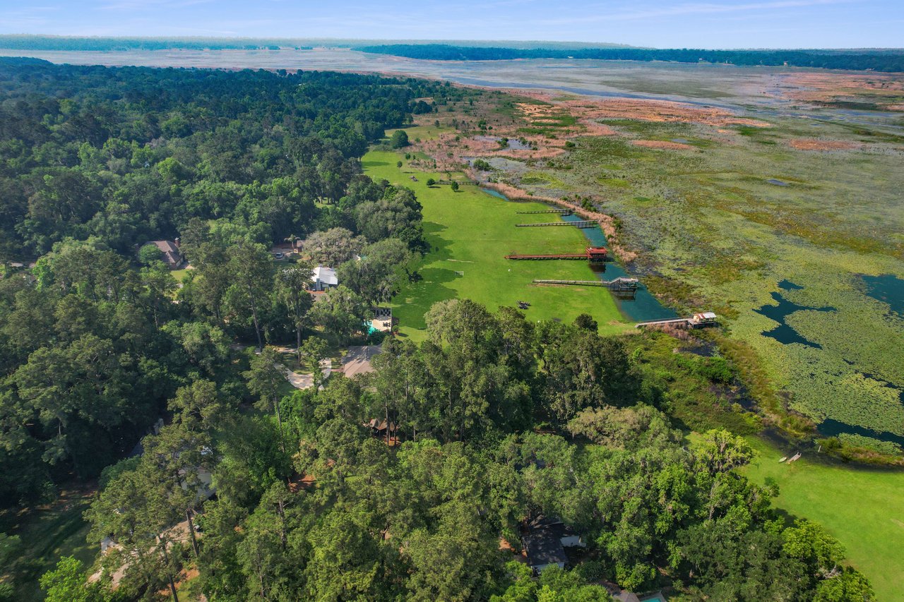 An aerial view of the Lake Breeze community, featuring houses near a large water body and surrounded by green landscapes.