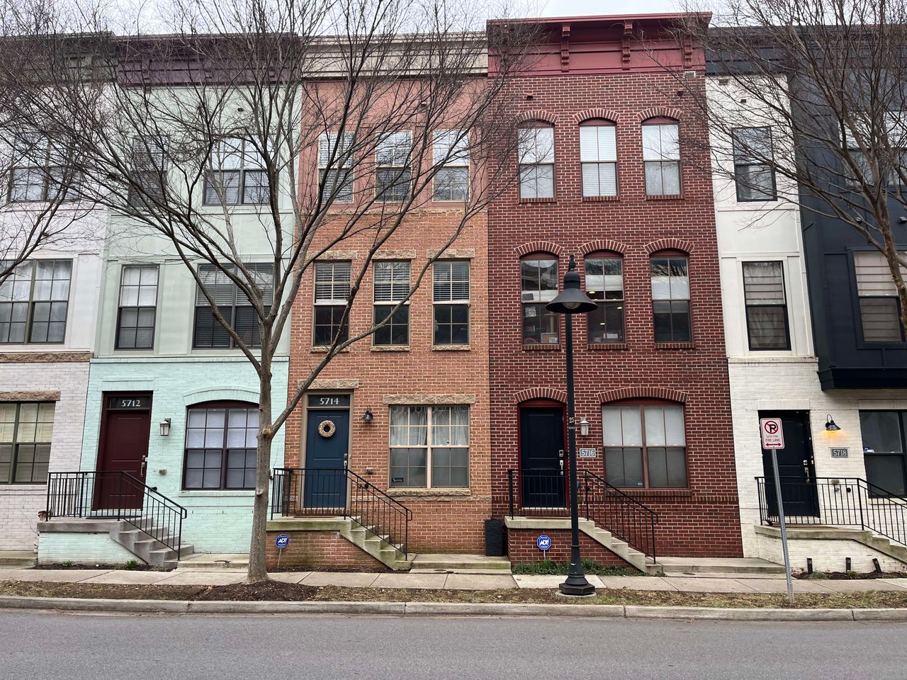  A row of four multi-story attached townhouses with diverse facades and colors