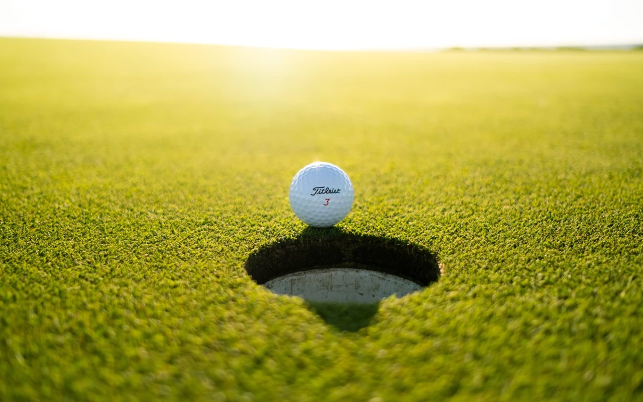 Golf ball in green grass near golf hole