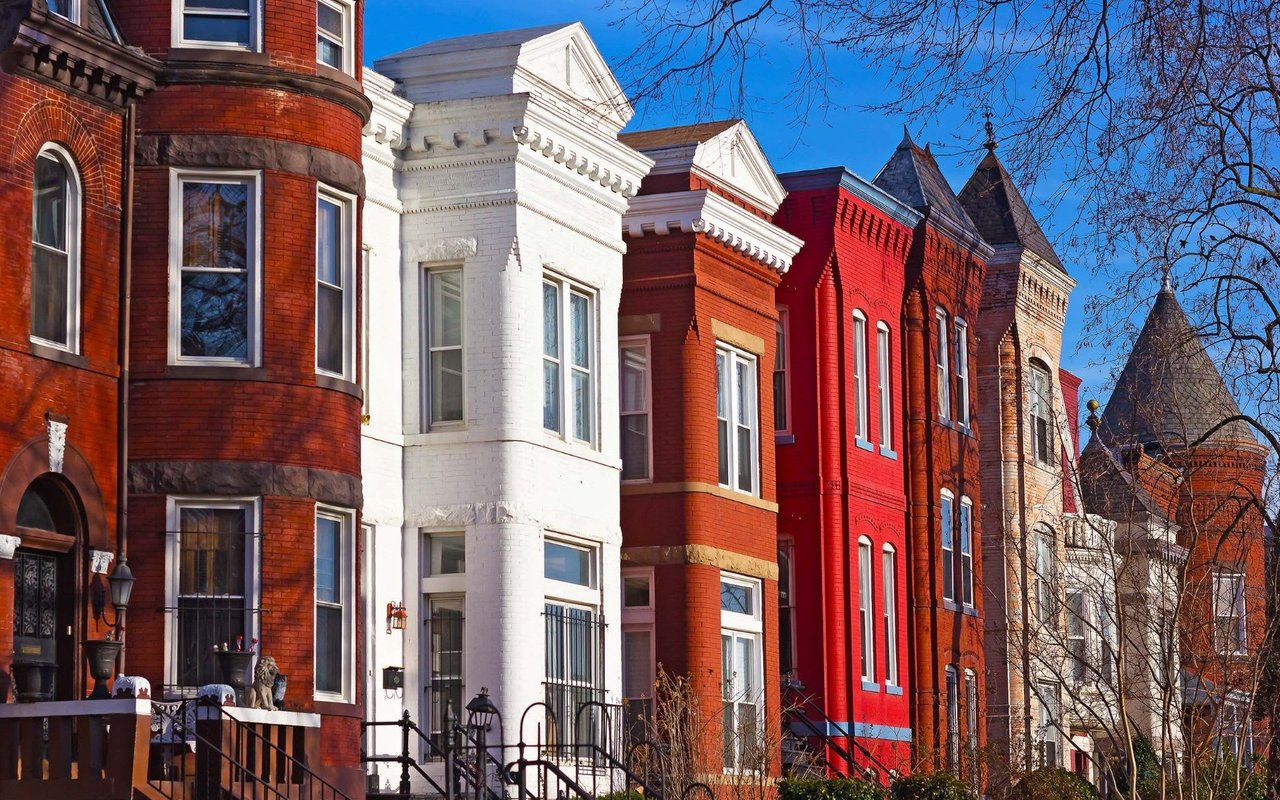 Each house has steps leading to a front door and is adorned with various windows