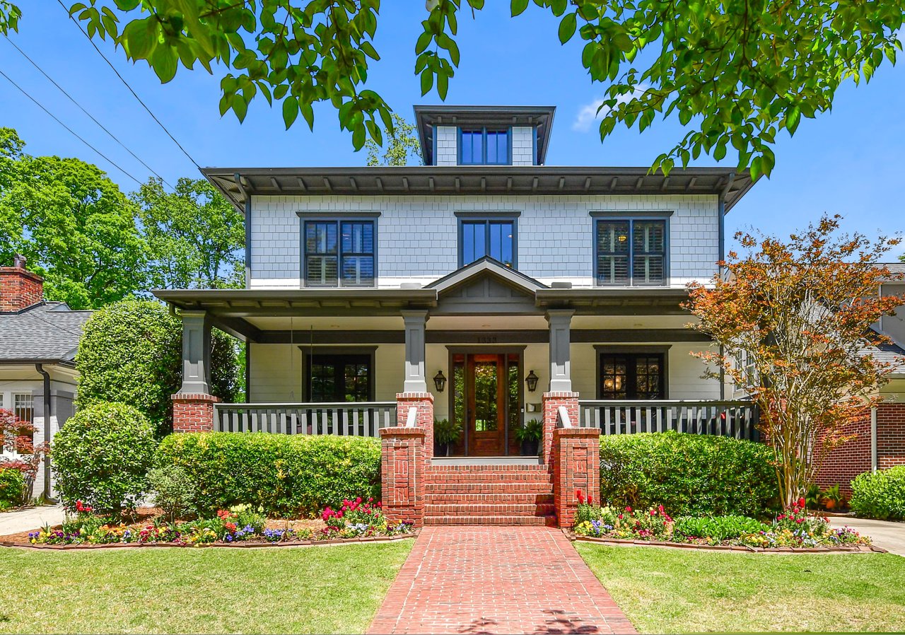 Virginia Highland, single-story ranch house with red brick walkway, covered porch with black railings, dormer windows, and front lawn.