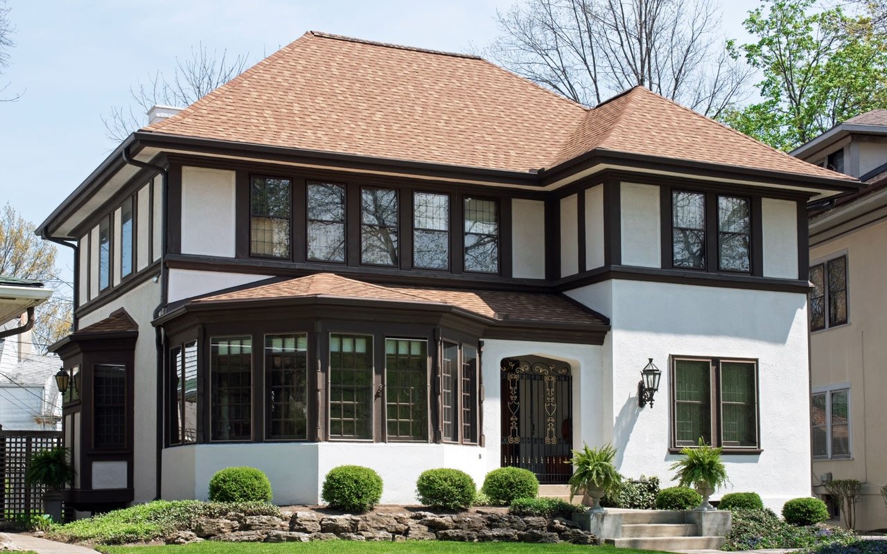 A large white house with brown stucco trim and a brown roof.