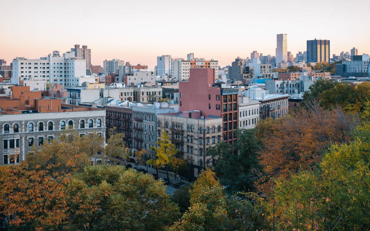 An aerial view of Morningside Heights in New York City, with brownstone buildings and fall foliage in the foreground