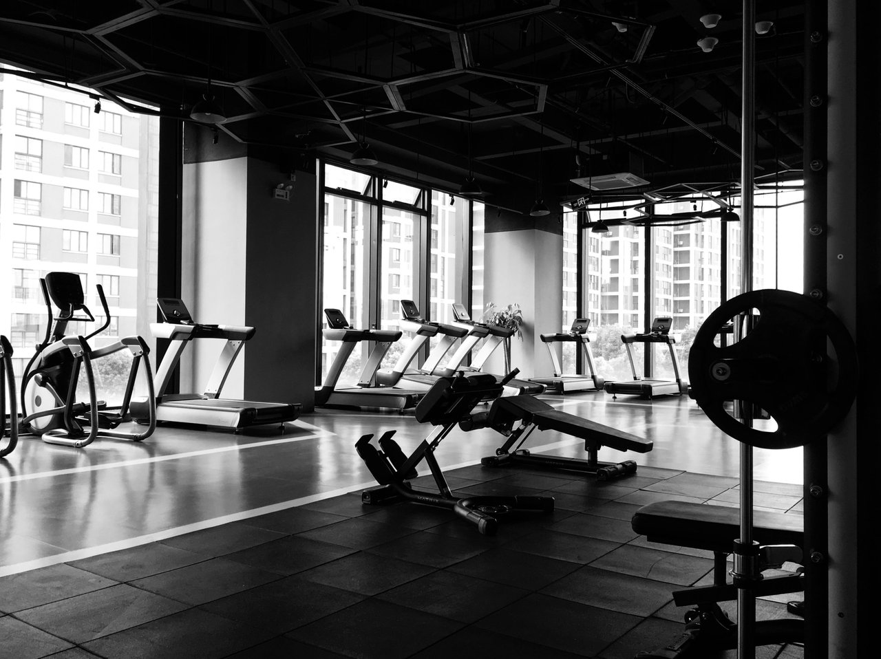 A well-equipped gym with weightlifting benches, barbells, and dumbbells in the foreground.