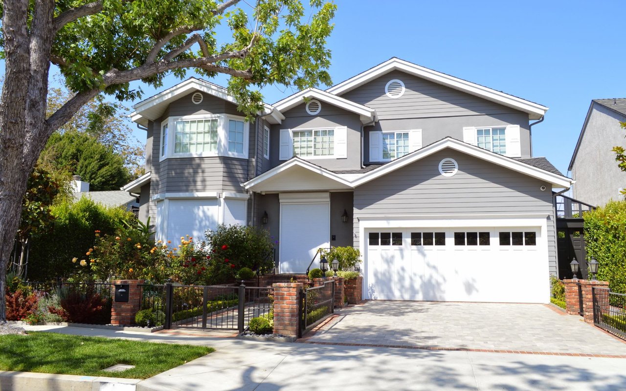  A charming two-story house with a grey exterior and white trim, featuring a prominent two-car garage with white doors. 