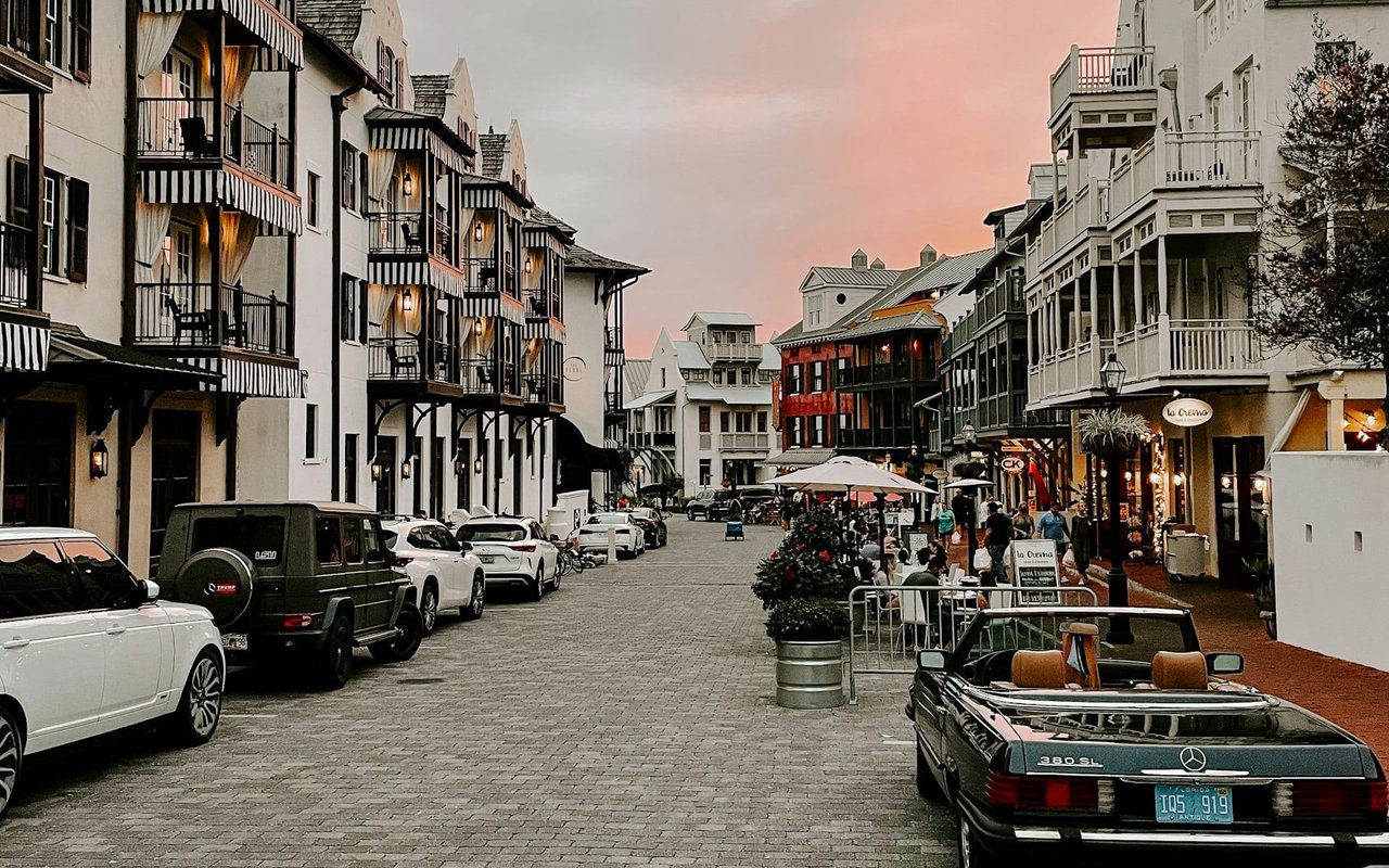 A charming, cobblestone street lined with colorful buildings in a coastal town. 