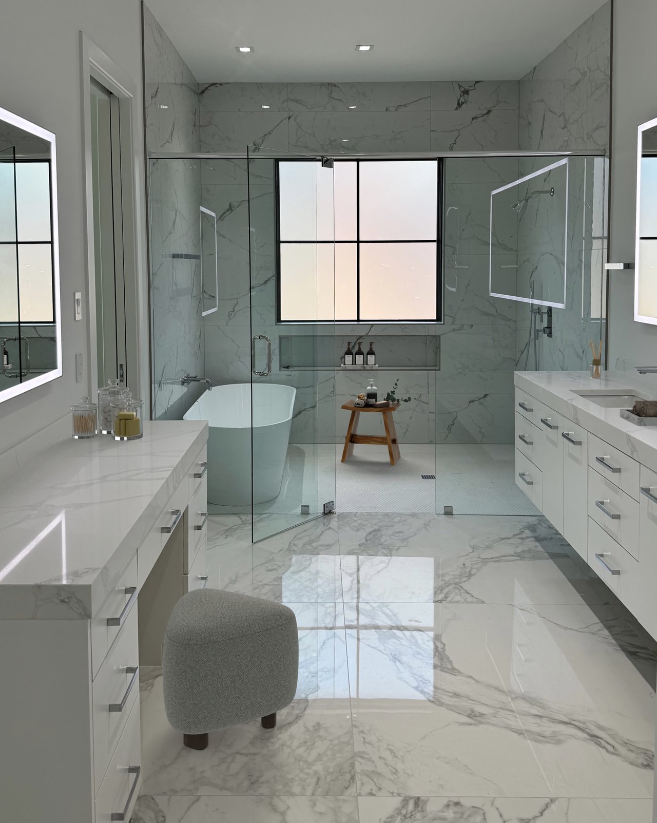 Modern marble bathroom with glass shower, freestanding tub, and sleek vanity by S&R Development on Del Norte