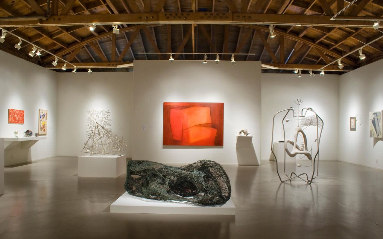  An art gallery with a high, vaulted wooden ceiling and exposed beams. 