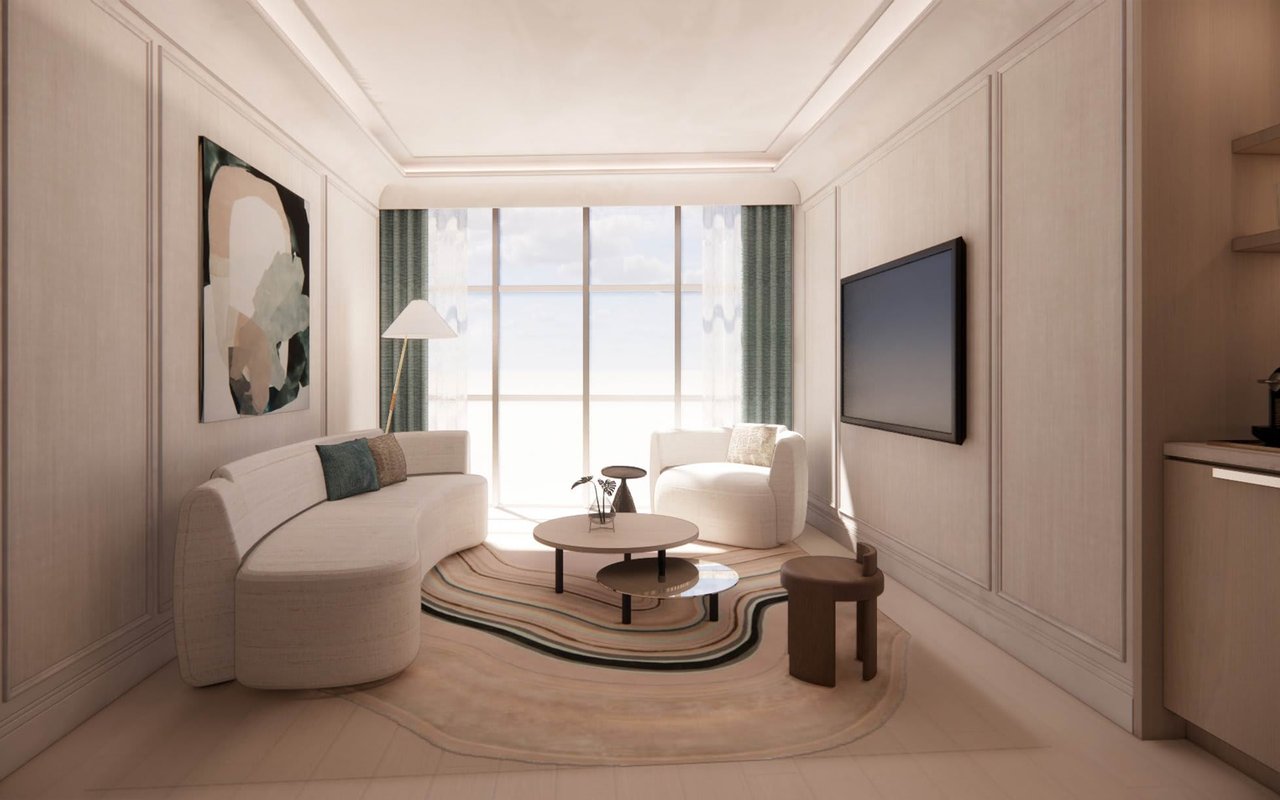 Living room with a curved cream sofa, layered coffee tables, and floor-to-ceiling windows.