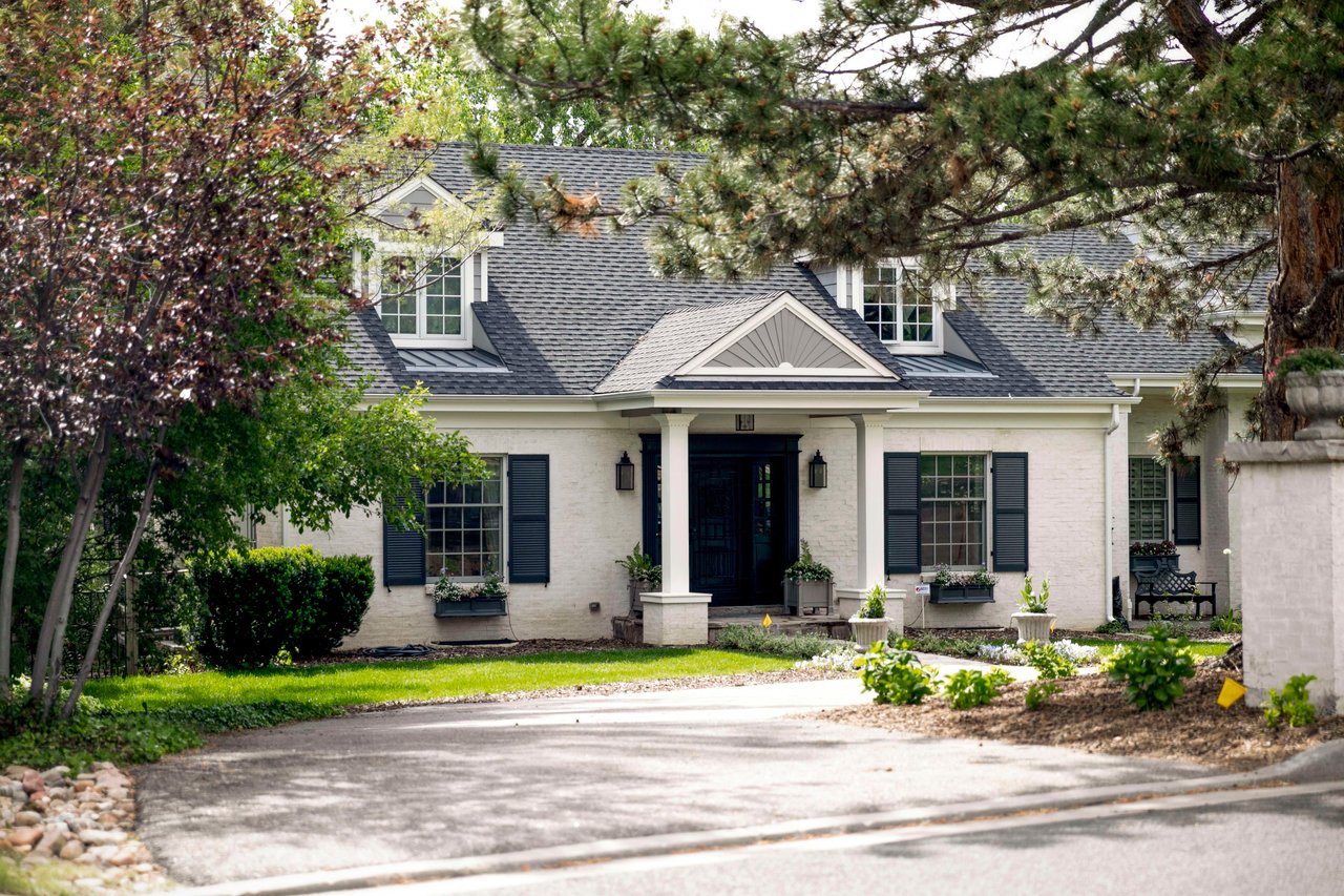 A white house with a gray roof and black shutters.