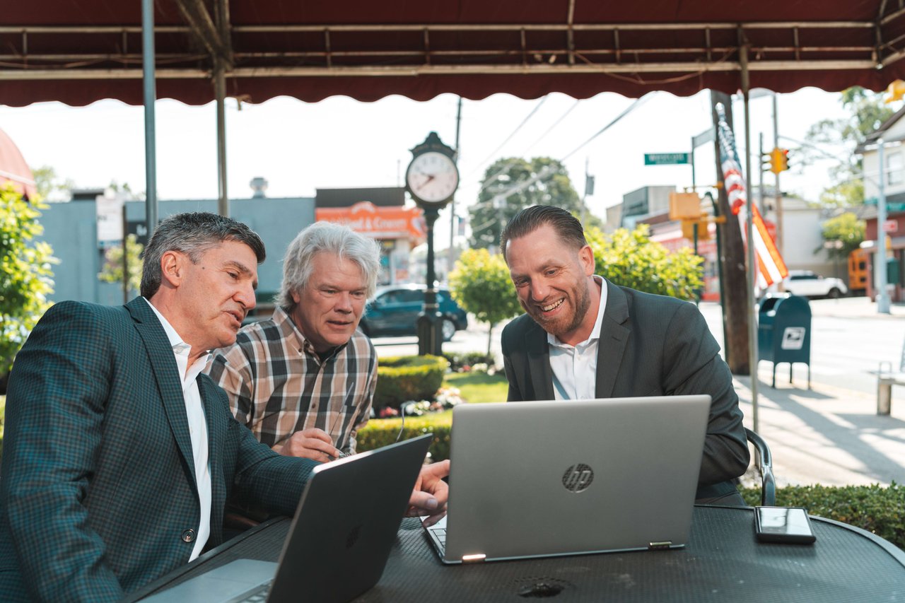 Joe Tirone and Compass Realty Agents Team reviewing on laptops