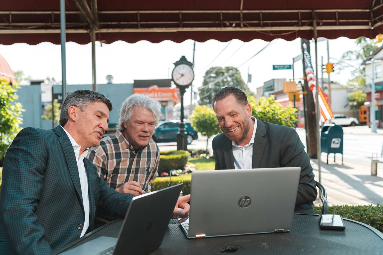 Joe Tirone and Compass Realty Agents Team reviewing on laptops