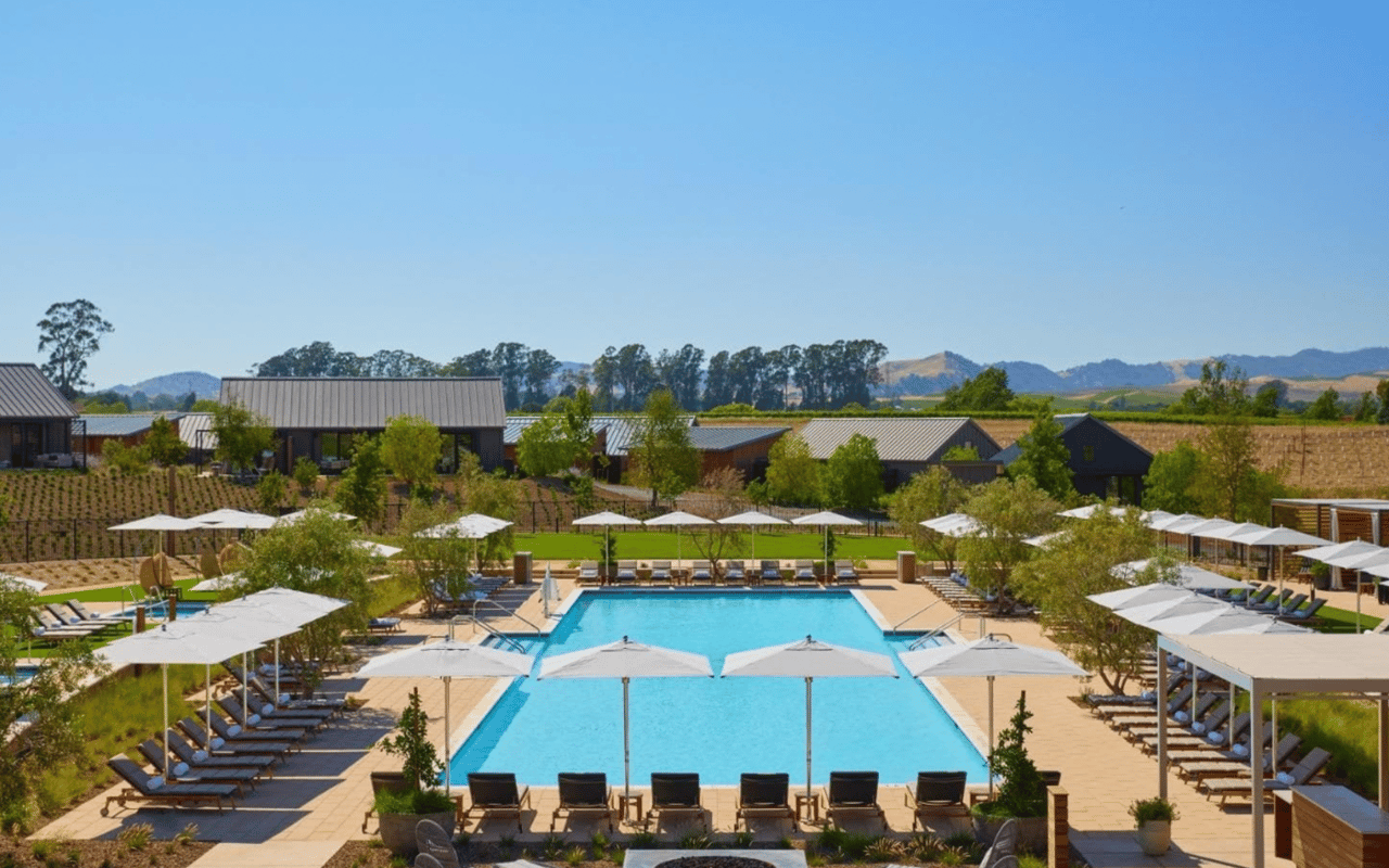 A large resort swimming pool with a lot of lounge chairs and umbrellas around it.