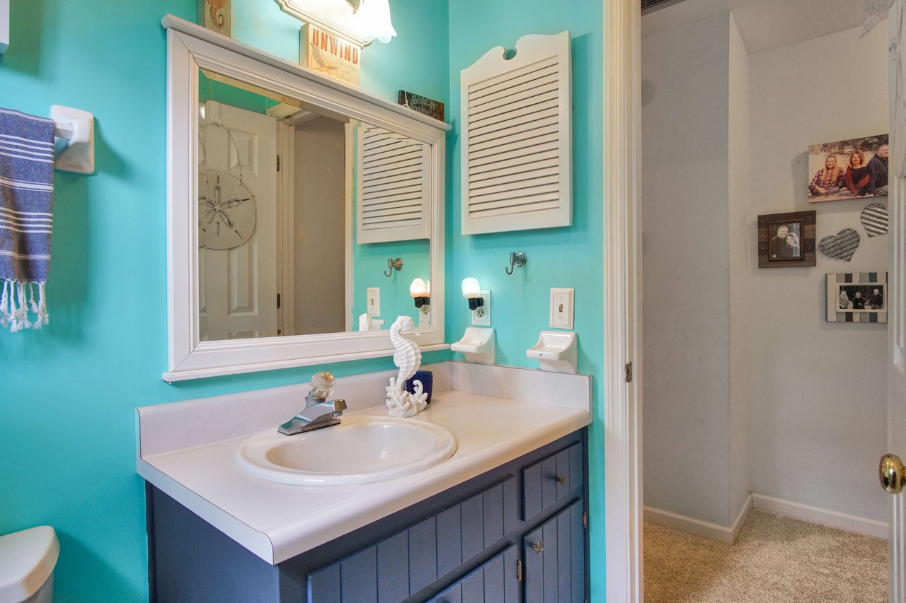 A view of the bathroom with a turquoise color theme focusing on the sink area. The sink has a mirror above it, and the room continues the turquoise color theme, giving it a vibrant look.