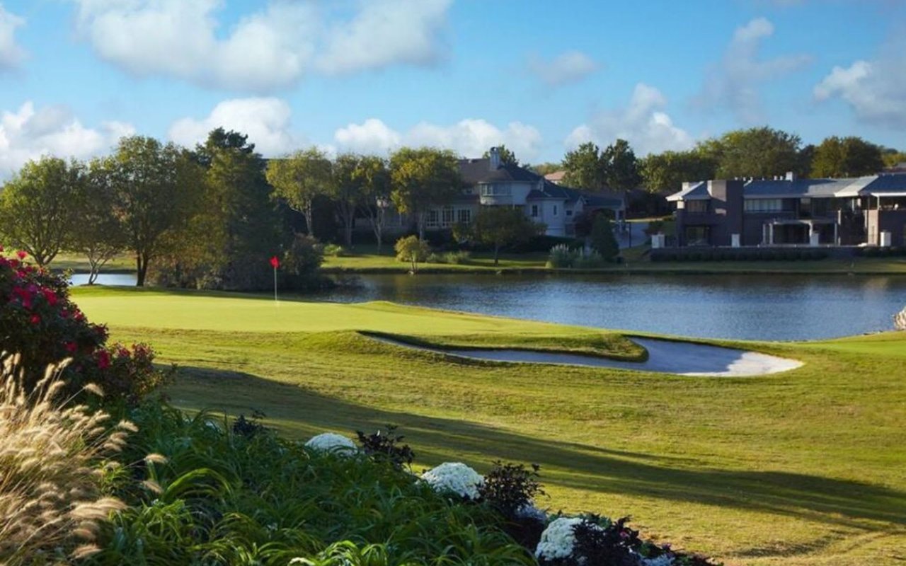 The Las Colinas Country Club in Irving, Texas with the iconic Cottonwood Valley course, a calm lake, and distant house views.