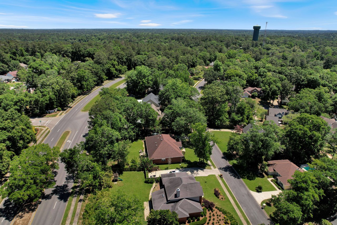 An aerial view of a residential neighborhood in Tredington Park with lots of greenery and houses surrounded by trees.