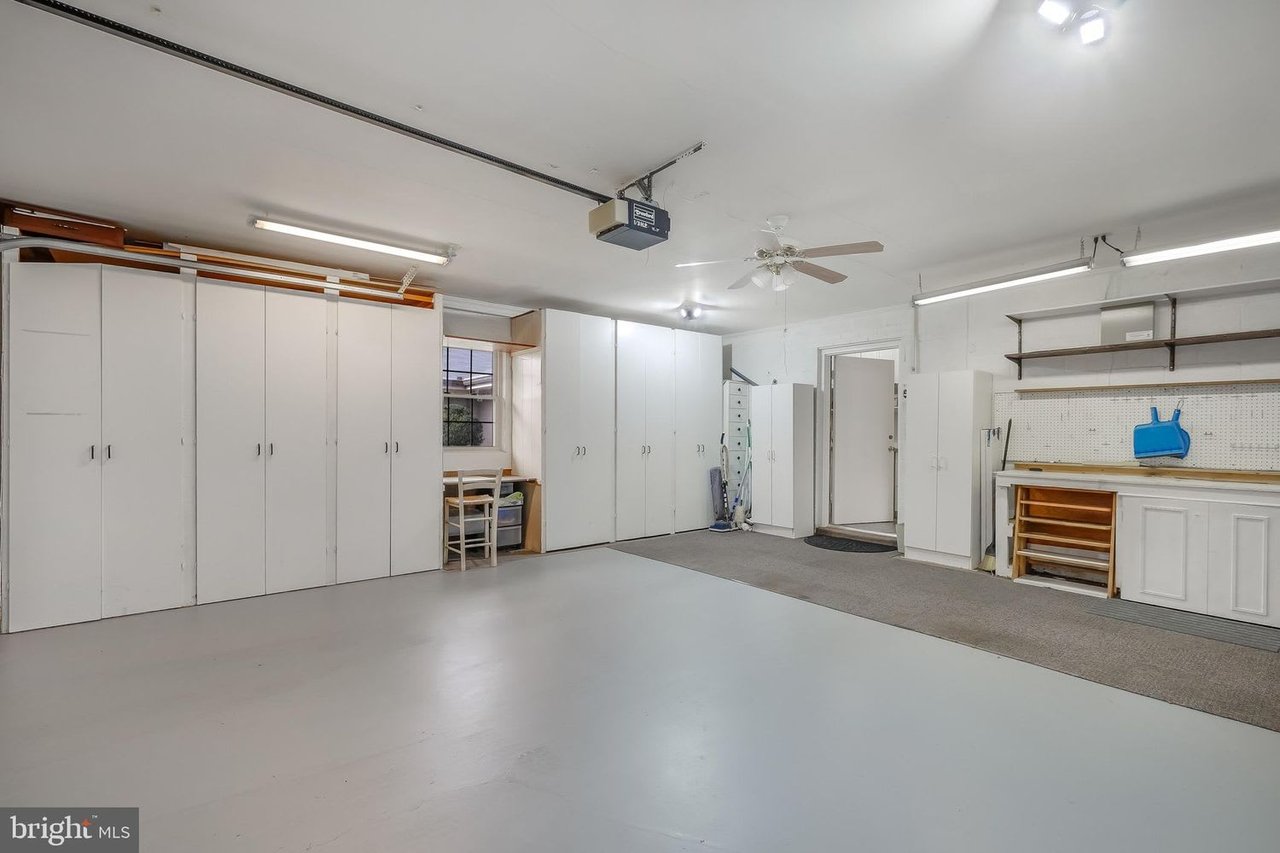 Garage with extensive white cabinets, a workbench, and a smooth gray floor.