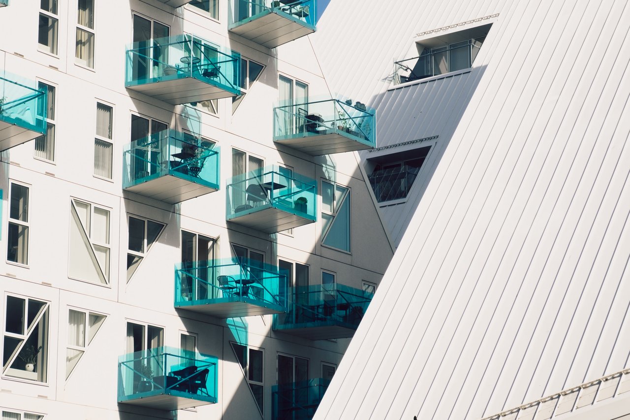 Modern apartment building with geometric windows and turquoise glass balconies.