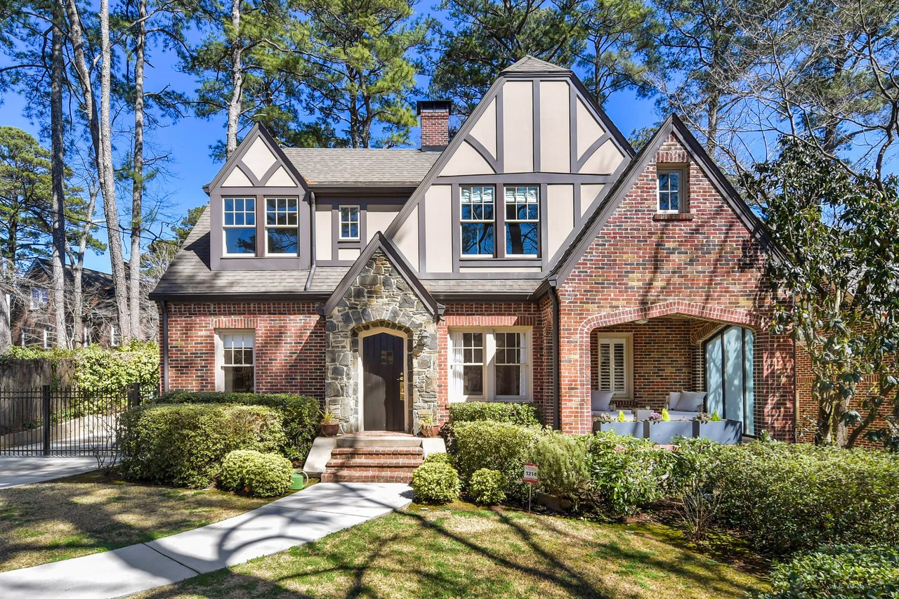 Two-story red brick house with a stone pathway, a slate roof, a chimney, a covered porch, and a two-car garage on the left.