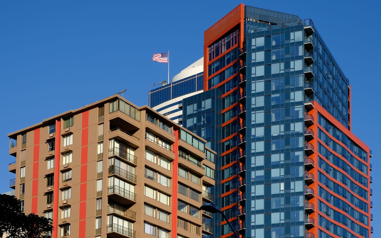  A low-angle shot showcases a mix of modern and older apartment buildings against a vivid blue sky.