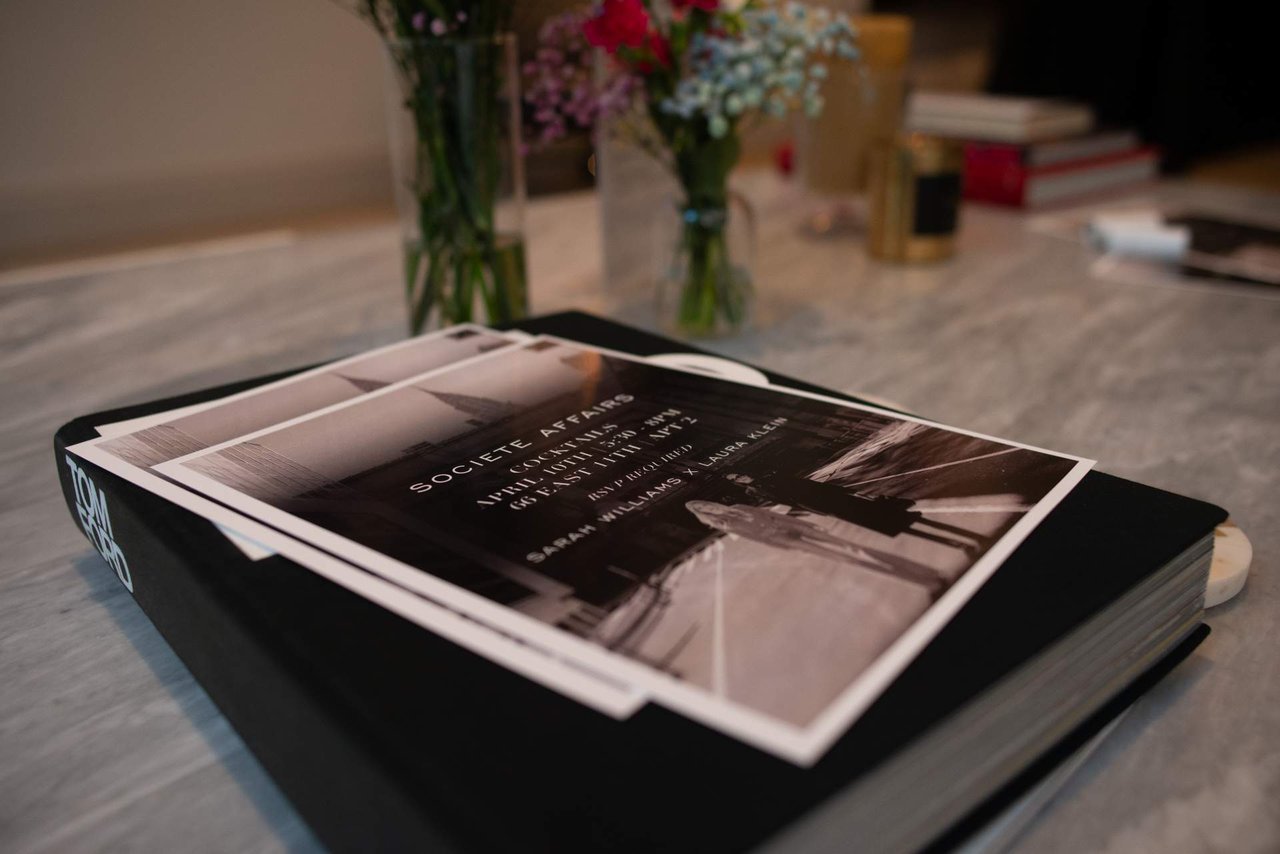 Societe Affairs booklet on a table, with event pages and flowers behind it.