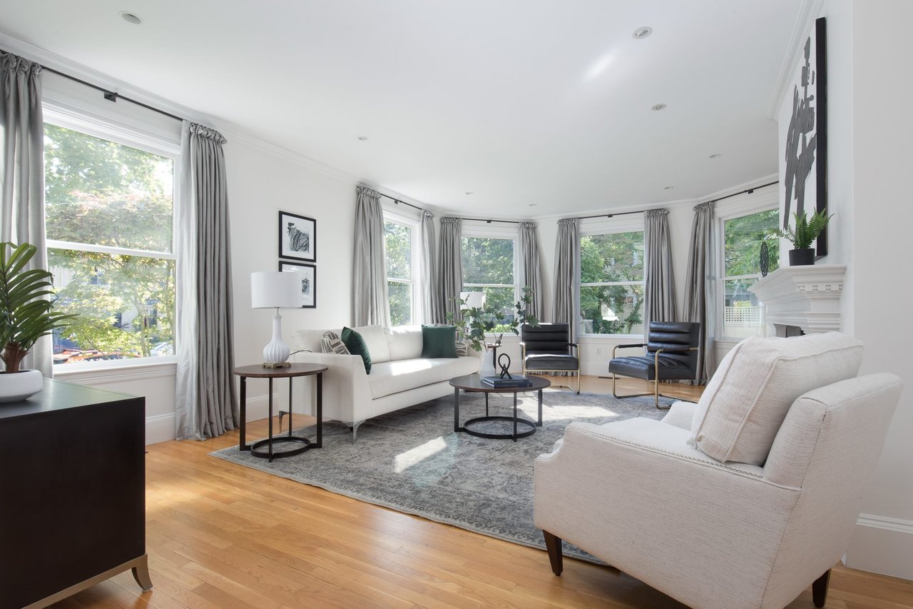 Bright living room with large windows, neutral furniture, and hardwood floors.