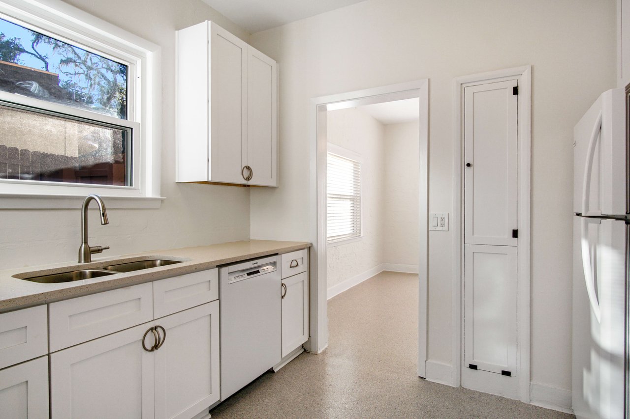 A view of the kitchen, focusing on the custom spice cabinets, white countertops, and modern fixtures.