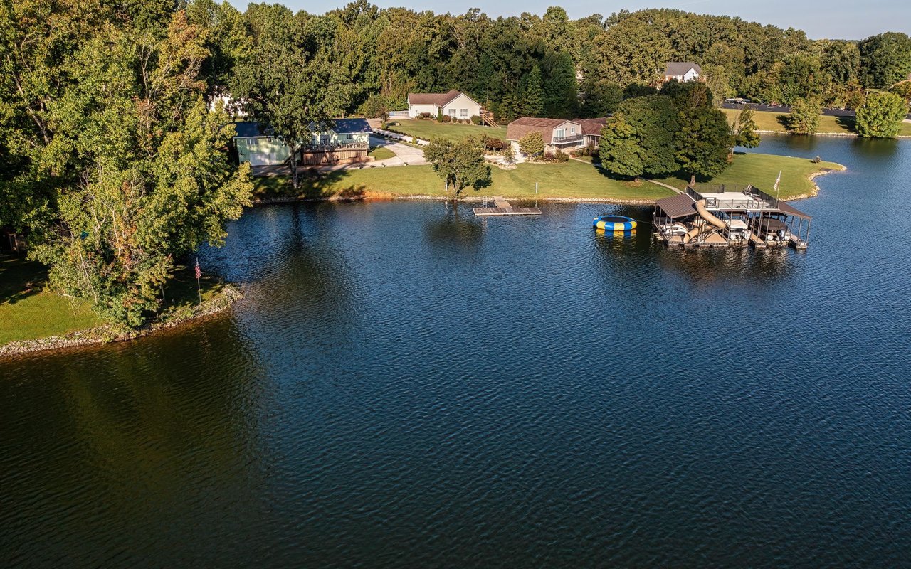 Aerial view of a lake with a wooden dock jutting out into the water.