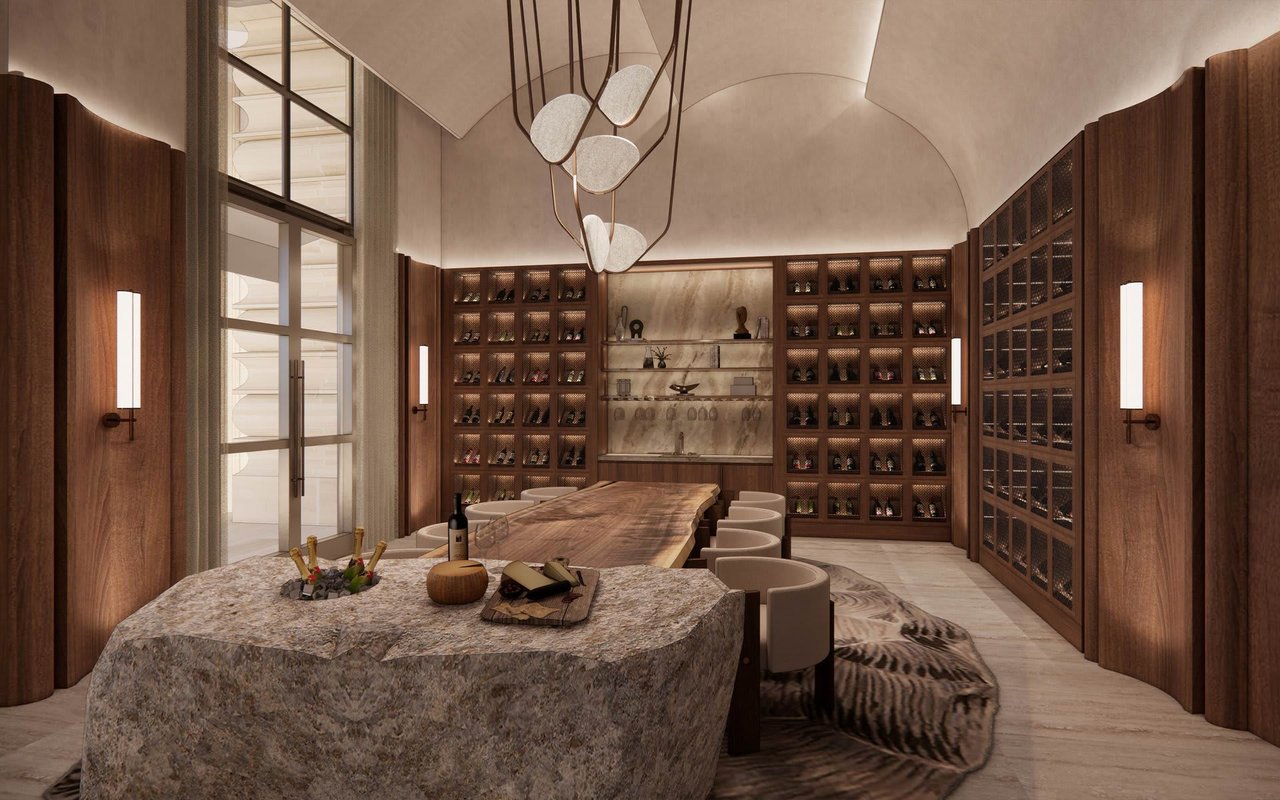 Wine room with illuminated bottle displays, a long tasting table and a sculptural stone island.