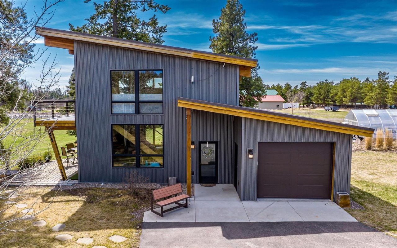 A modern house with a dark gray corrugated metal exterior and a light wood-trimmed, slanted roof.
