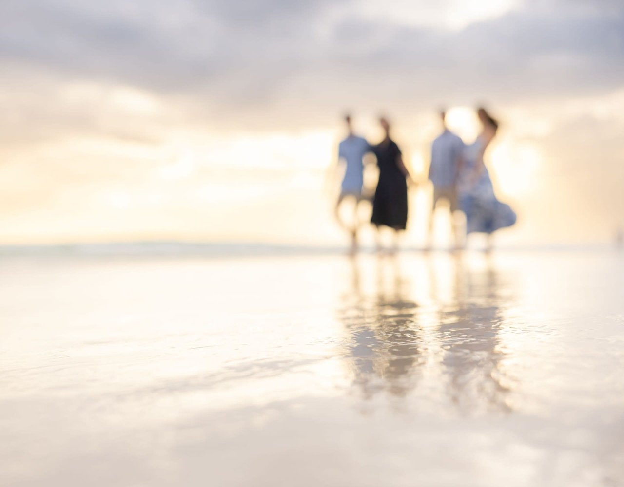 Family of four, blurry in distant background, walking on the beach near 30A.
